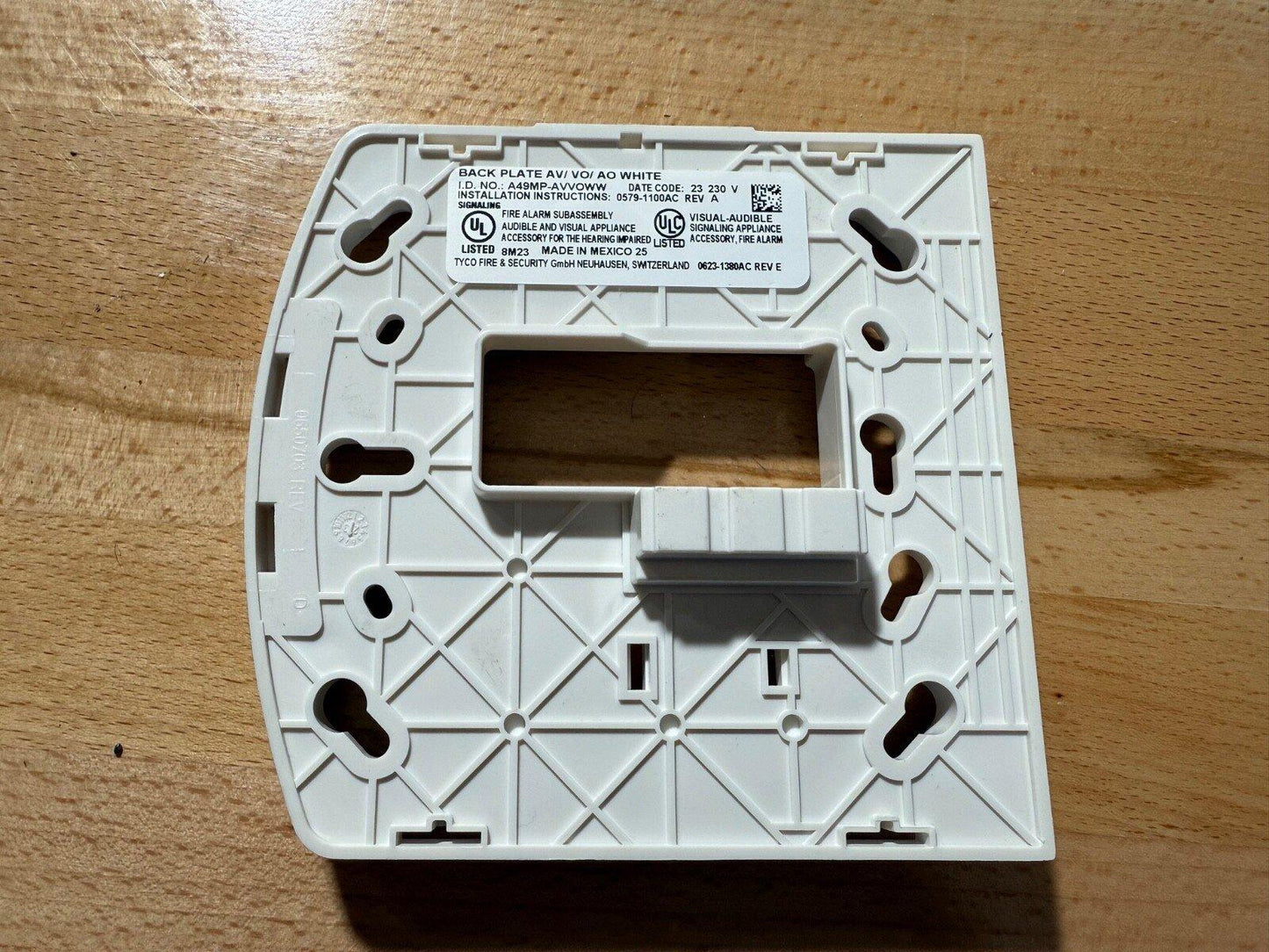 White fire alarm back plate with UL listing, mounting holes, and installation label for audible/visual signaling