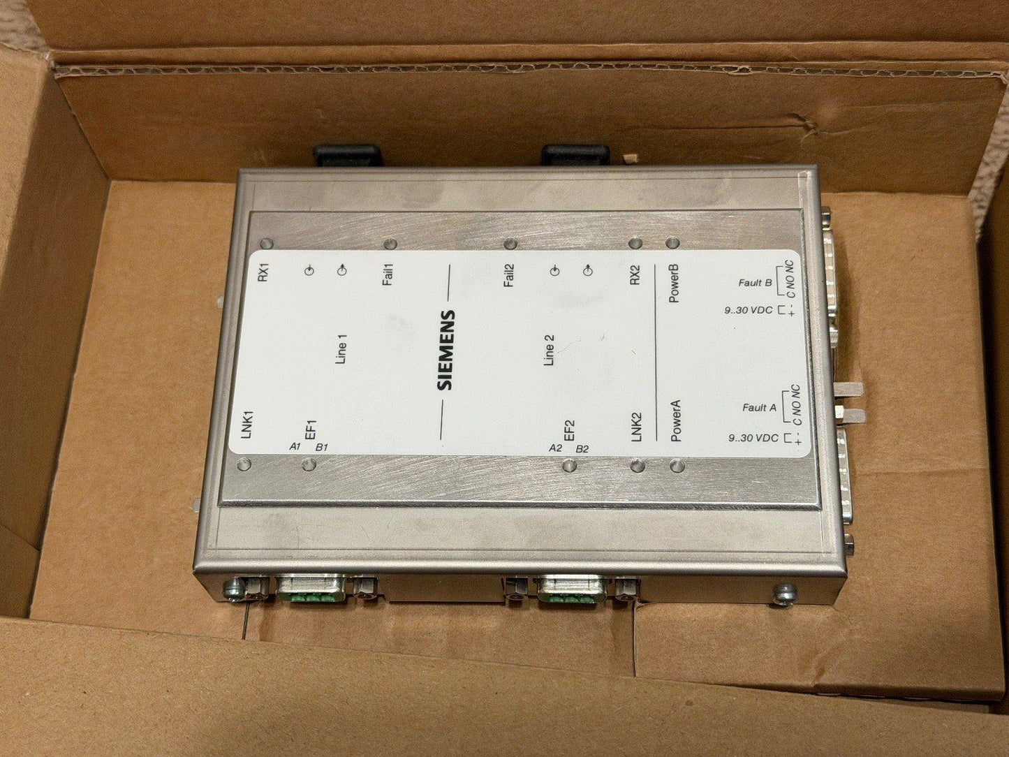 Siemens fire alarm control module in shipping box, labeled with Line 1, Line 2, Power A/B, and fault indicators