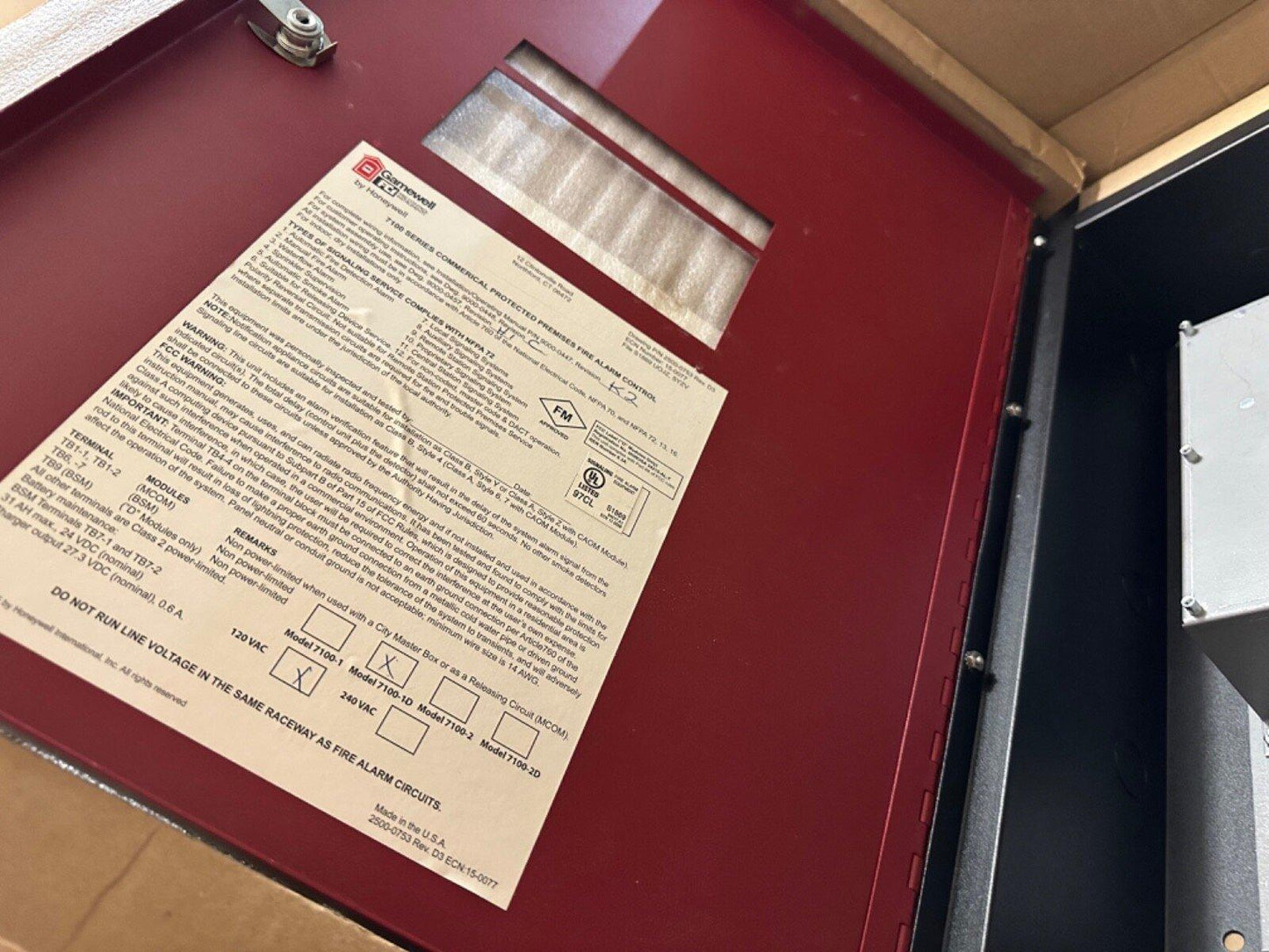 Red fire alarm control panel with label, showing Honeywell 7100 series specs and certifications for commercial use