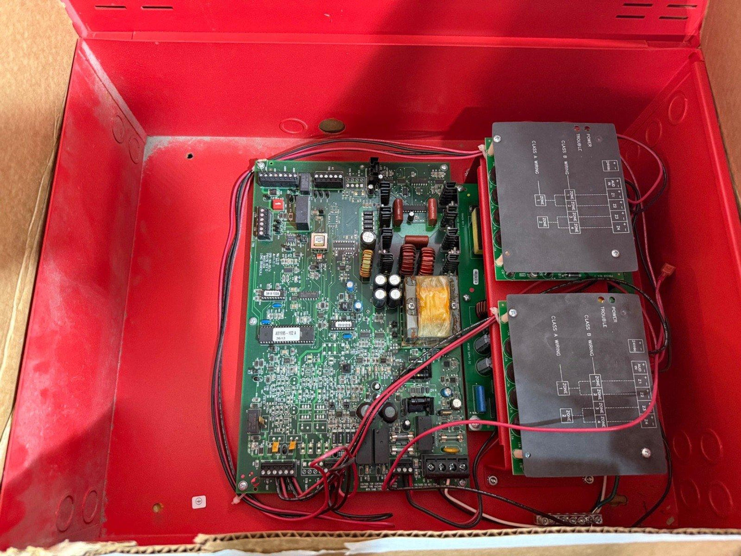 Fire alarm control panel circuit board with wiring inside red enclosure, used fire alarm equipment