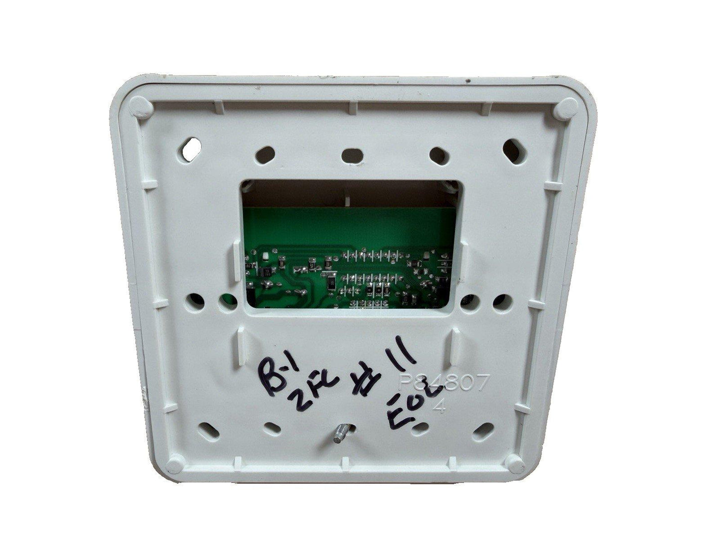 White fire alarm control panel back with green circuit board and handwritten markings