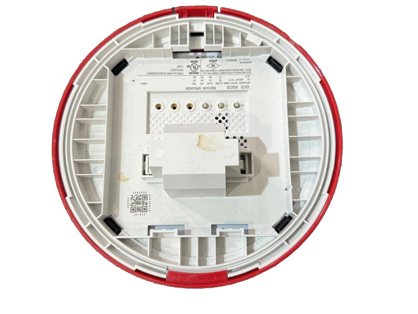Back view of white fire alarm speaker with red trim, showing wiring terminals and UL label for indoor use