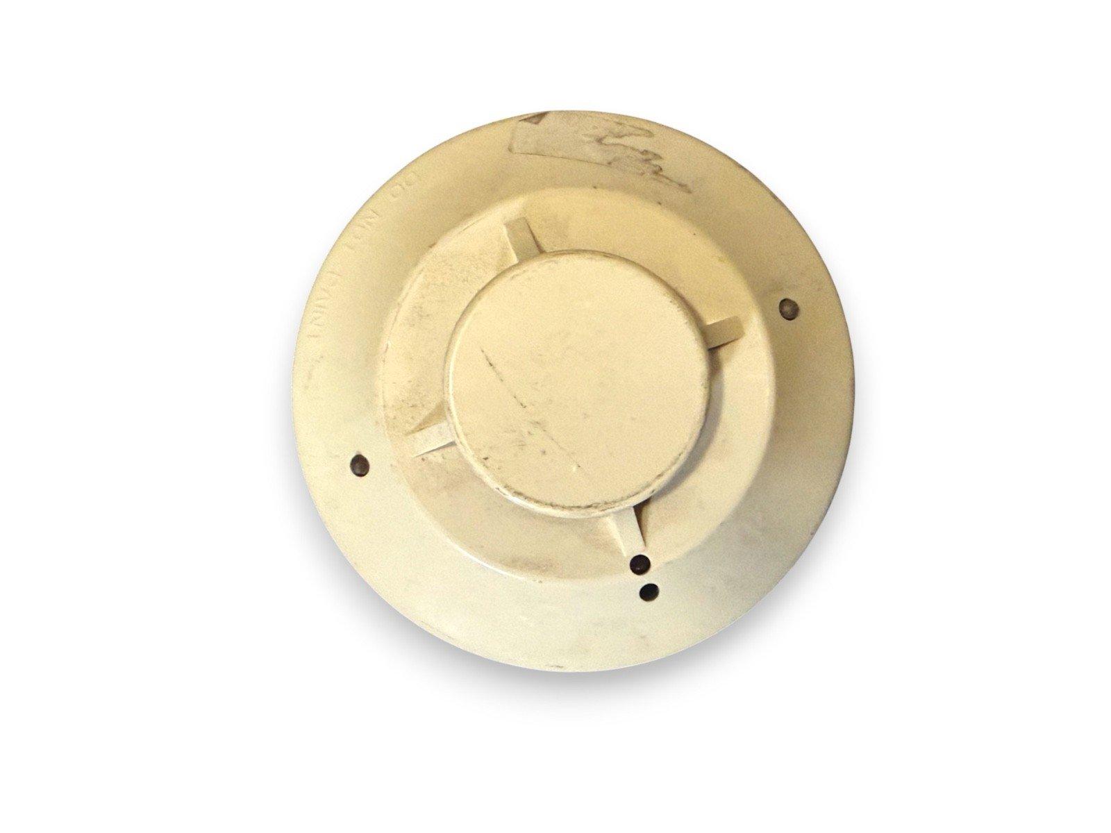 Used fire alarm smoke detector with mounting holes, off-white circular base for ceiling installation