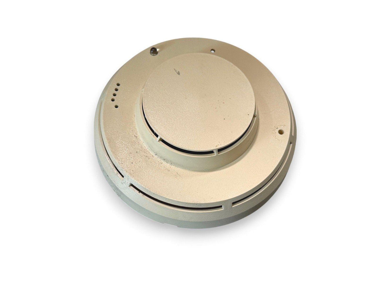 Beige fire alarm detector with mounting holes and vents, used fire safety equipment