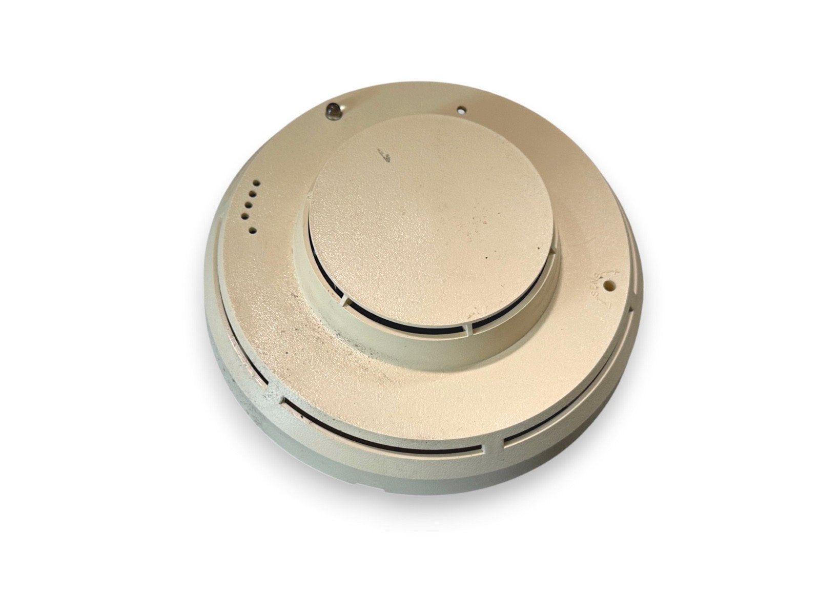Beige fire alarm detector with mounting holes and vents, used fire safety equipment