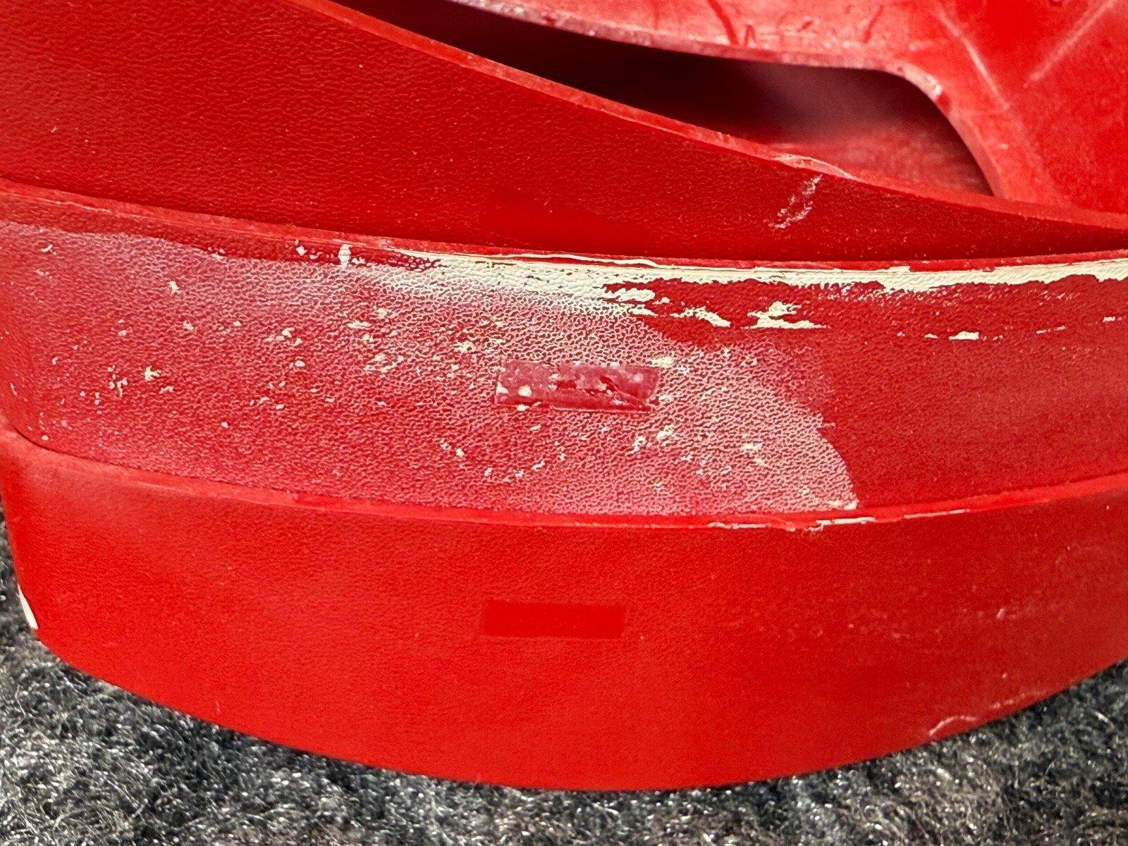 Red fire alarm device with chipped paint, showing wear on textured surface