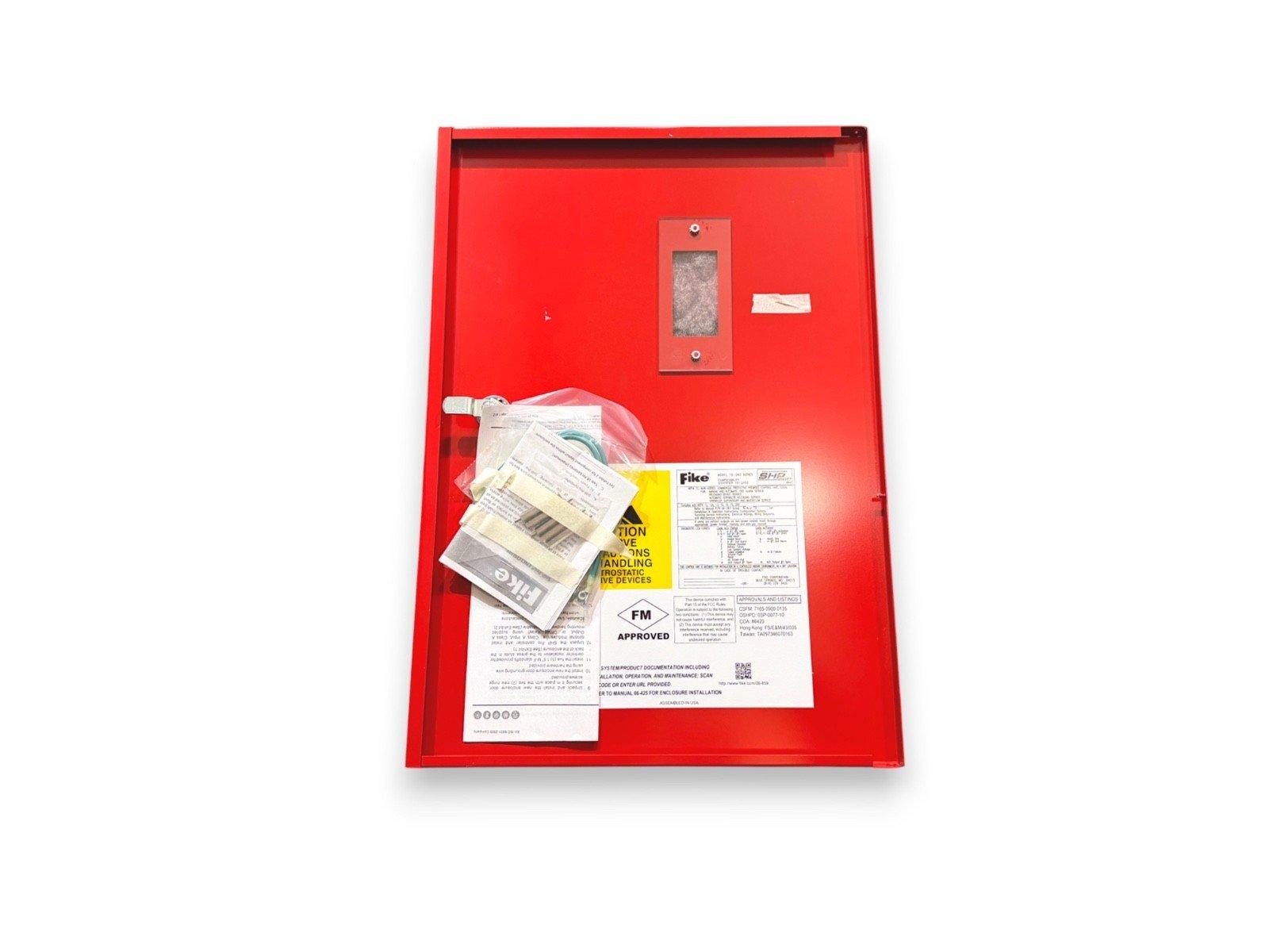 Red fire alarm control panel with Fike documentation and FM approved label, ready for installation