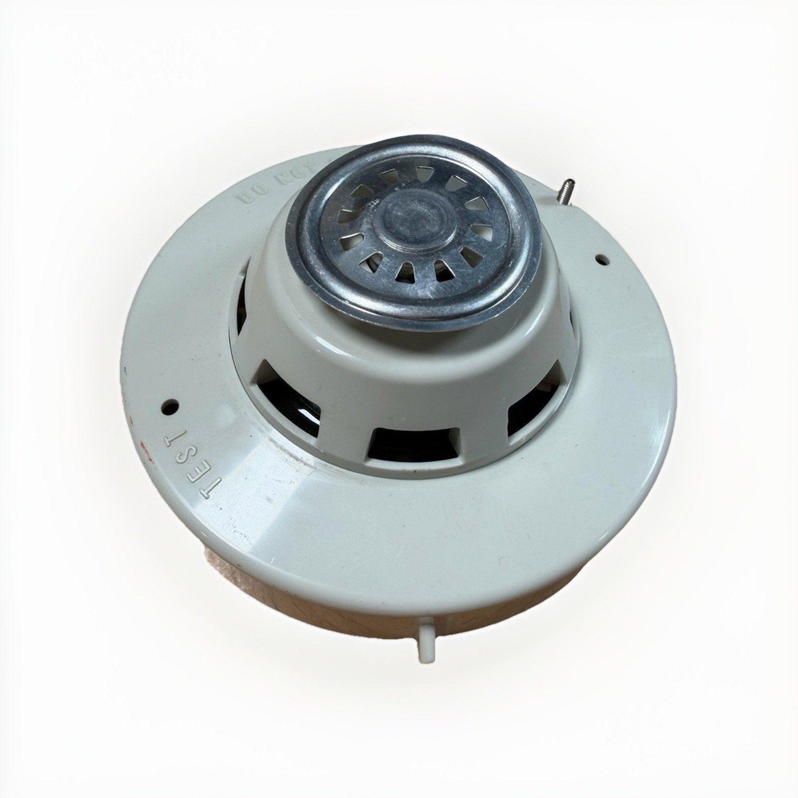 White ceiling-mounted fire alarm detector with test button and vented design