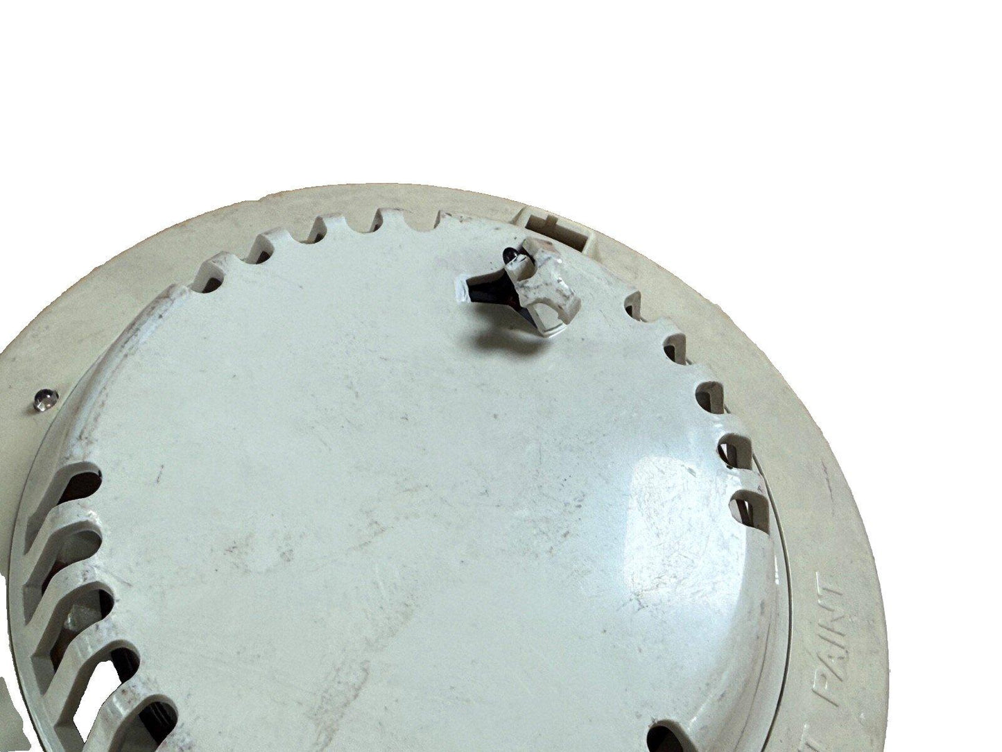 Used fire alarm detector with mounting bracket and ventilation slots, white ceiling sensor