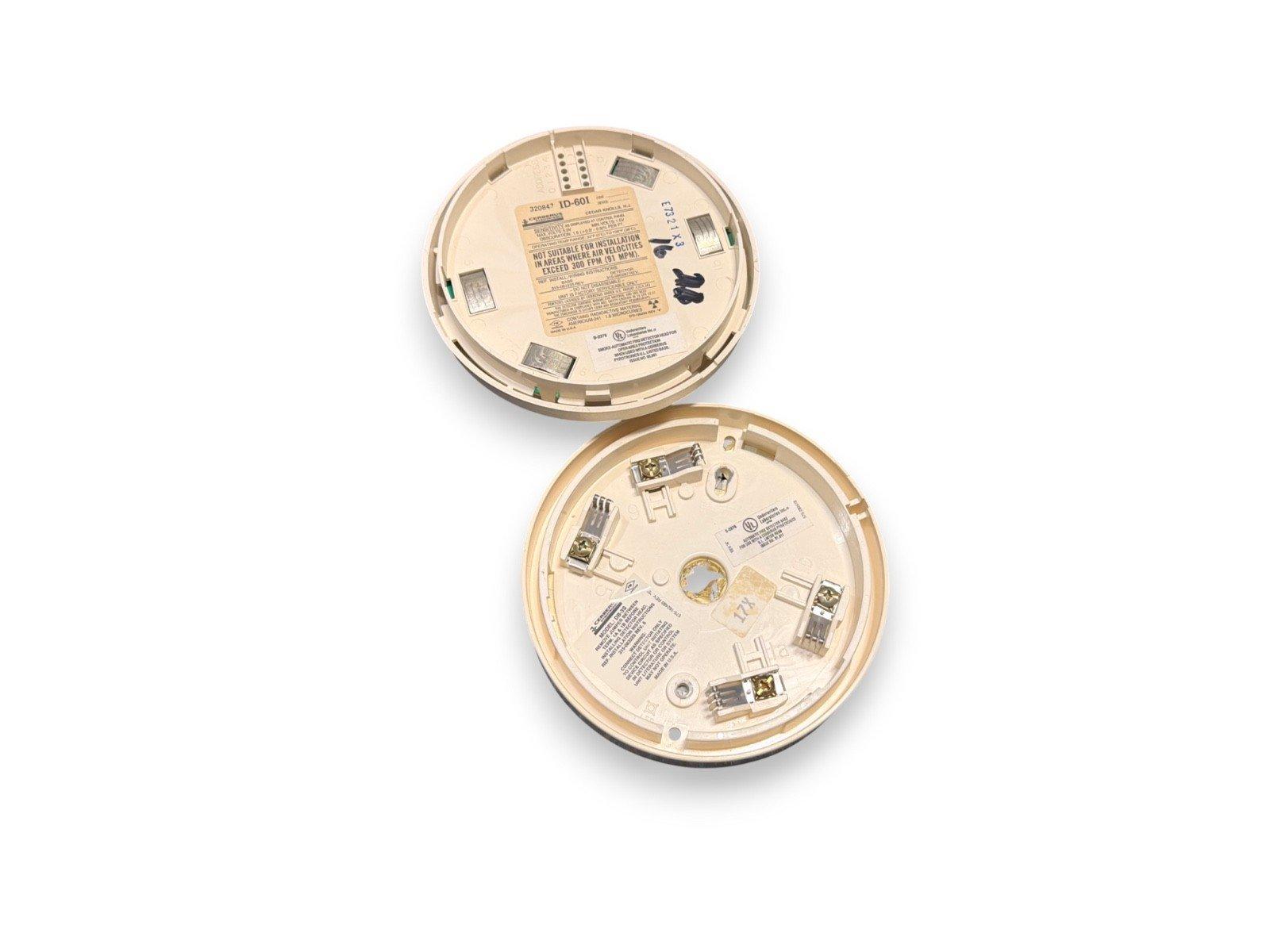 Two beige fire alarm detectors with wiring terminals and installation labels, shown from underside view