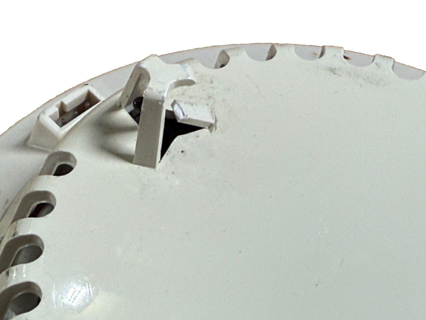 White fire alarm detector base with mounting clips and screw holes, used fire alarm equipment