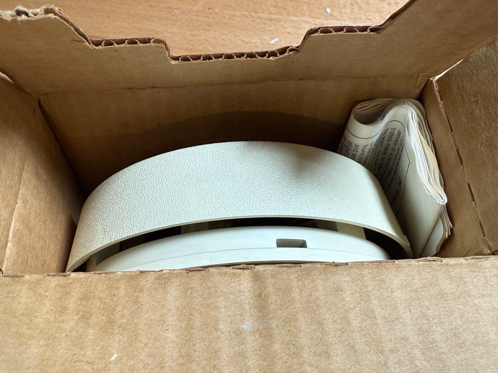 White fire alarm detector in cardboard box with manual, ready for installation