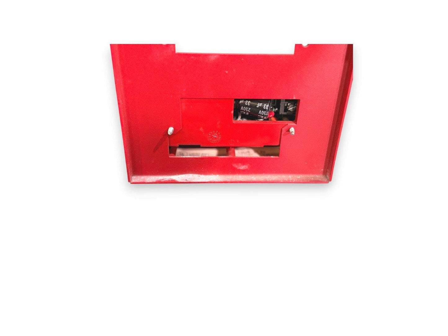 Red fire alarm control panel with exposed internal wiring and capacitors, used fire safety equipment
