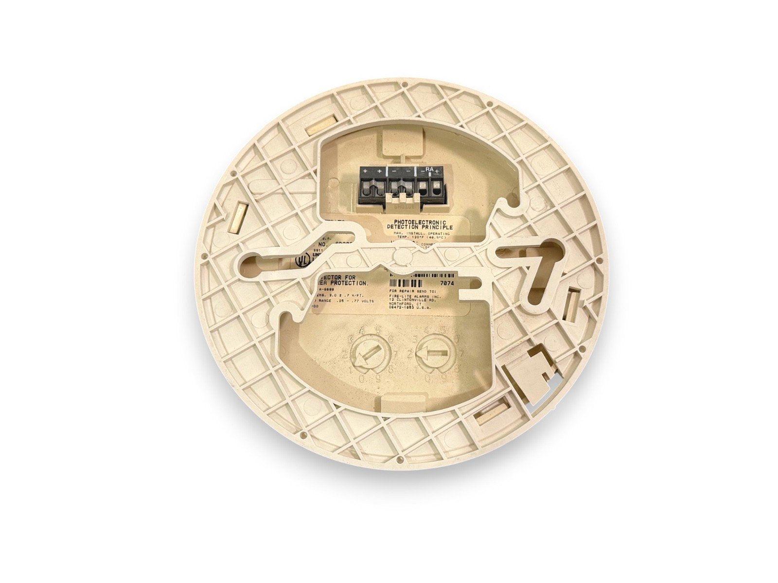 Back view of photoelectric smoke detector with wiring terminals and installation labels for fire alarm systems