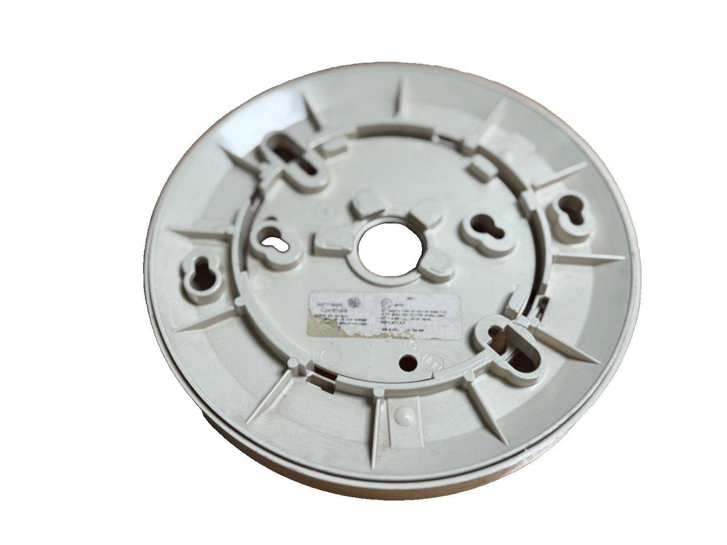 White fire alarm base with mounting slots and central hole for detector installation
