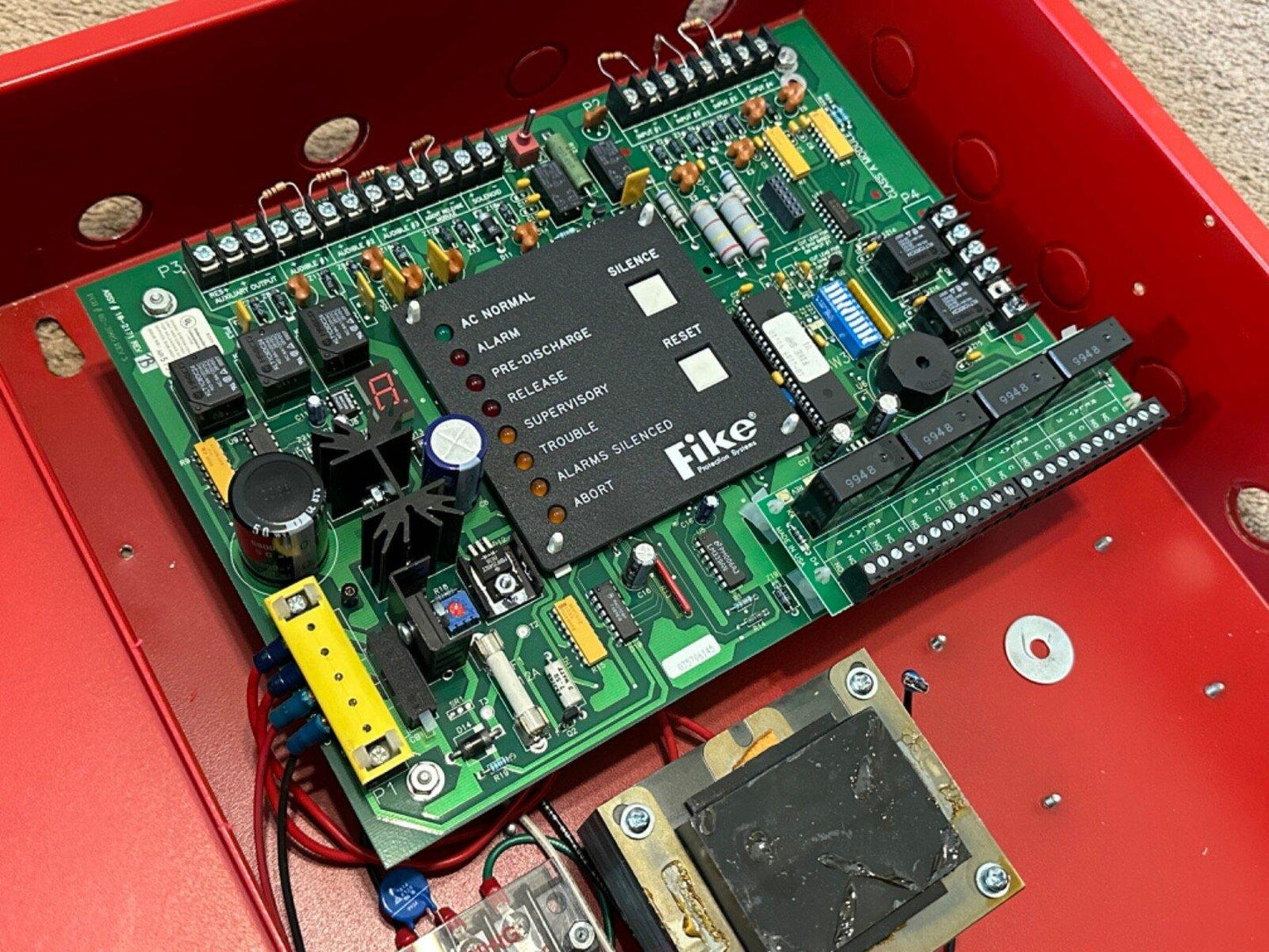 Fike fire alarm control panel circuit board with status LEDs and terminal connectors inside red enclosure