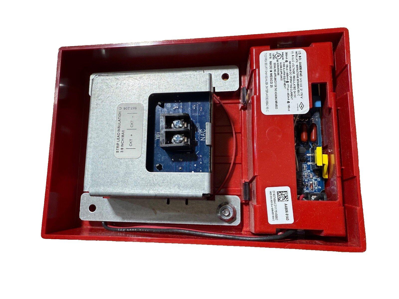 Red fire alarm control panel with internal circuitry and wiring terminals for fire safety systems