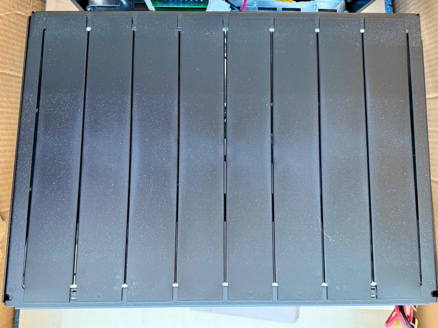 Black fire alarm control panel with slatted cover, showing internal wiring and components