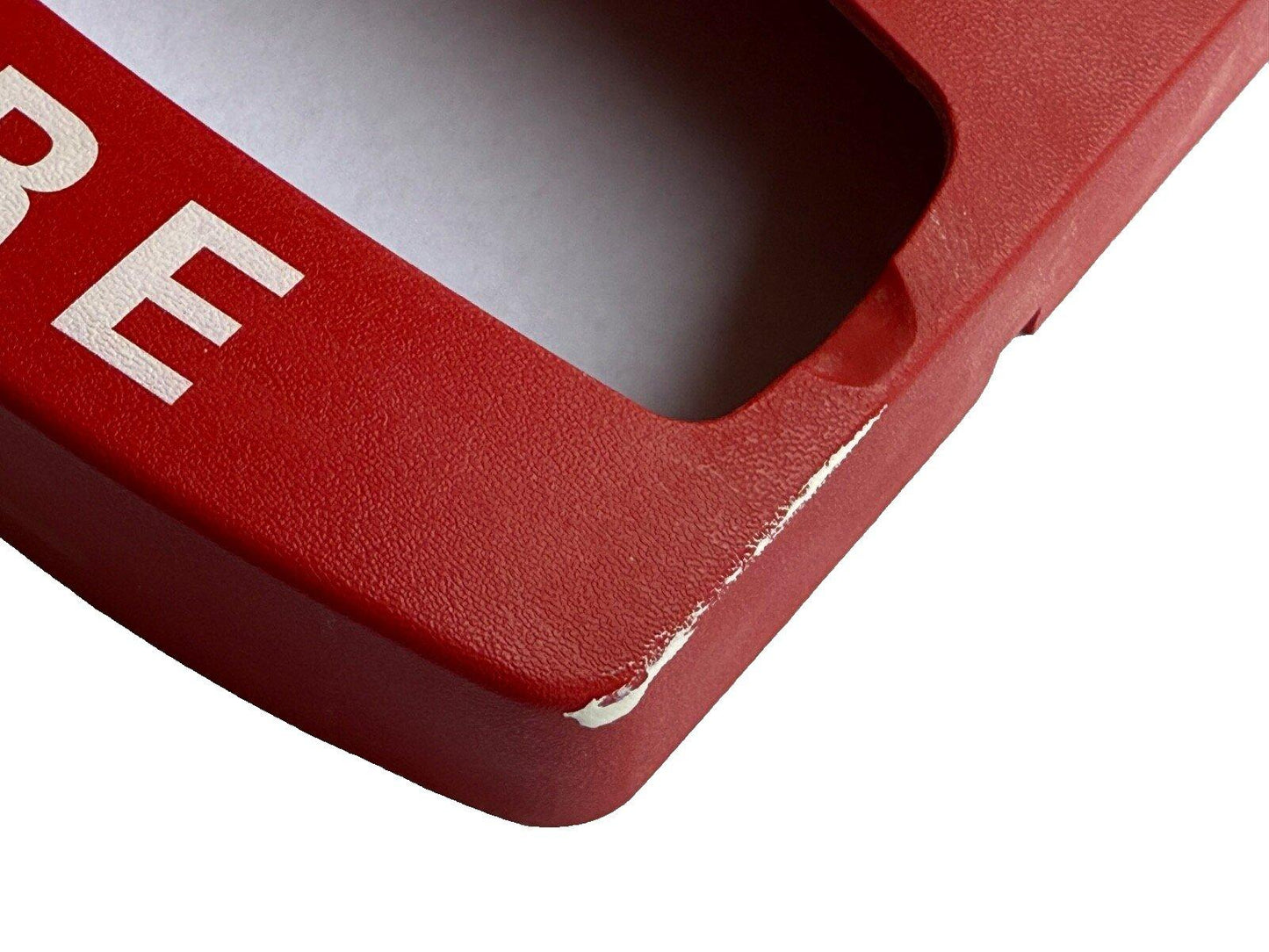 Red fire alarm pull station cover with white lettering, showing wear on edge