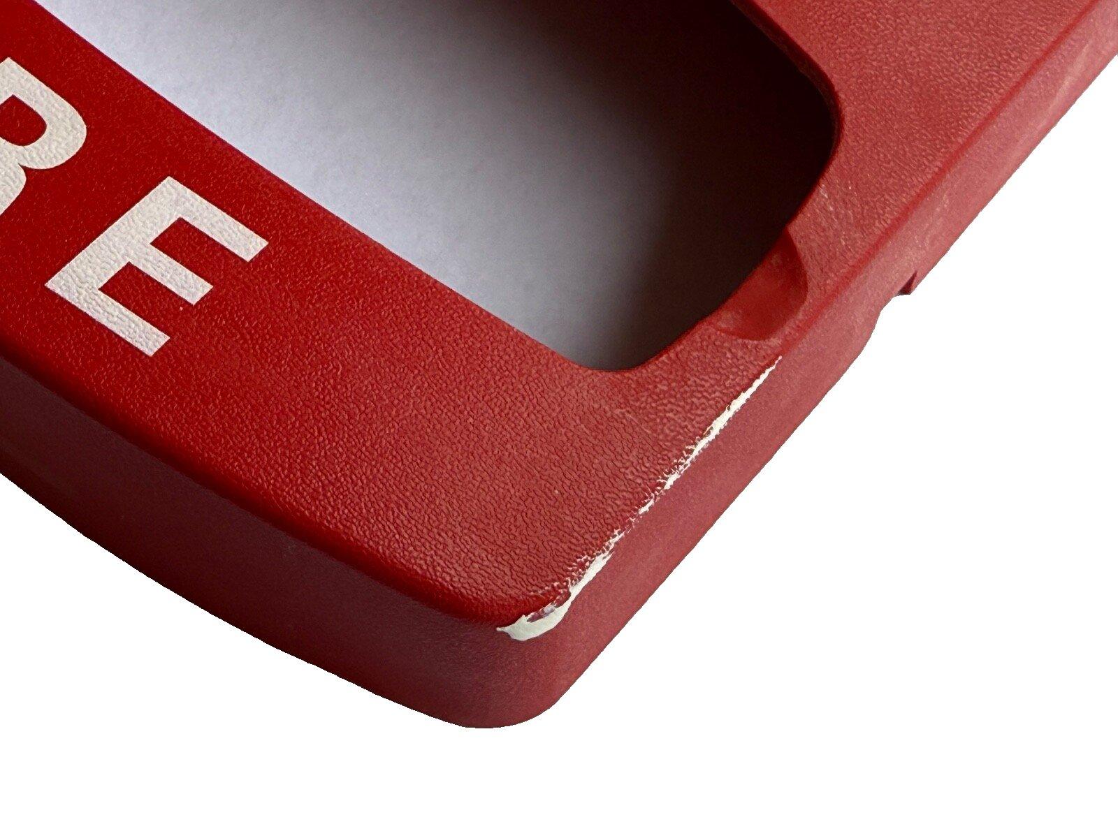 Red fire alarm pull station cover with white lettering, showing wear on edge