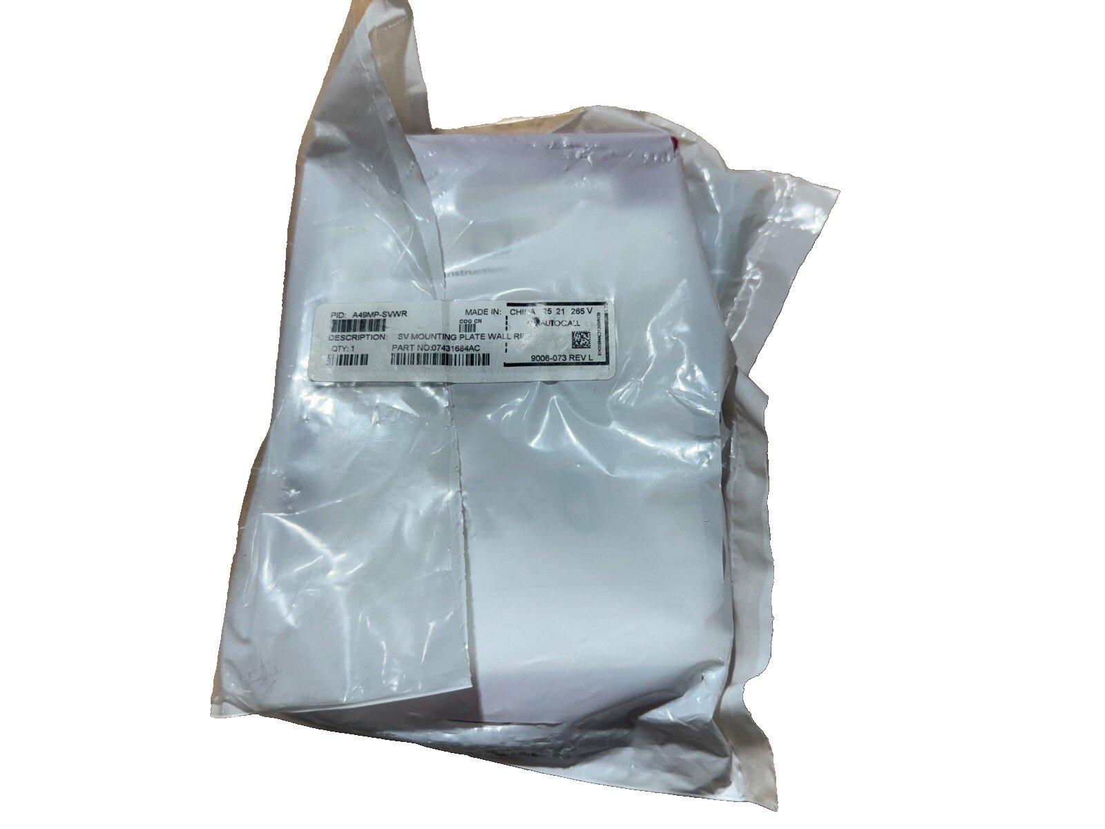 Sealed fire alarm mounting plate in plastic packaging, labeled SV Mounting Plate Wall, part number 07431684AC
