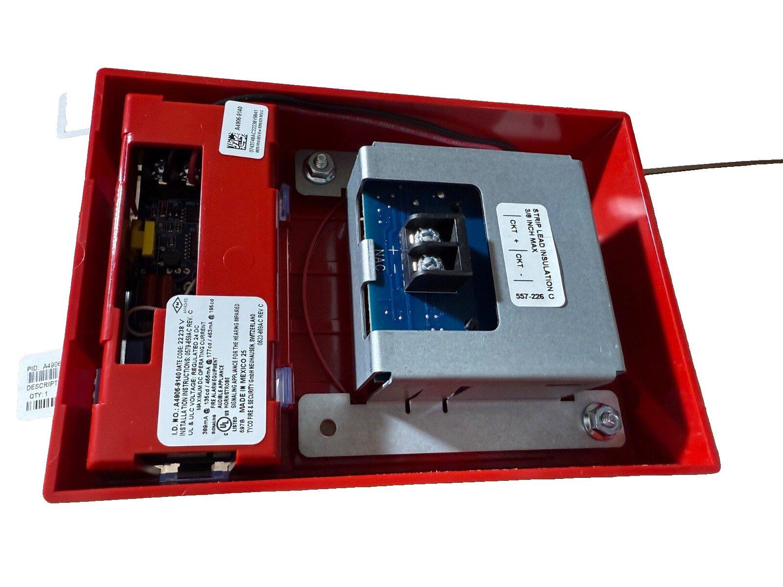 Red fire alarm control panel with internal circuitry and transformer, labeled for installation and safety compliance