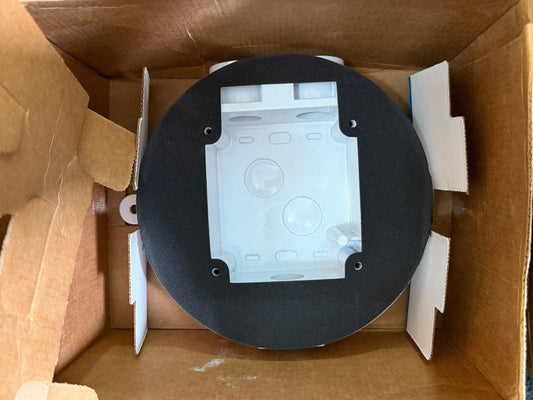 Fire alarm base with black mounting ring in cardboard box, ready for installation