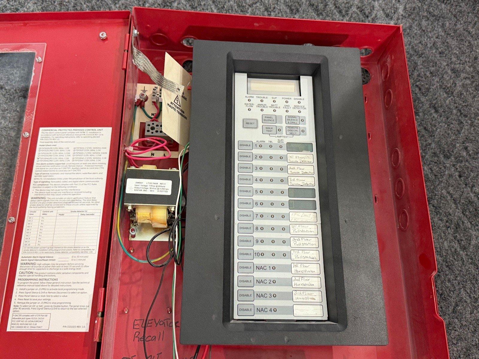 Fire alarm control panel with labeled zones and wiring, housed in red enclosure for commercial use