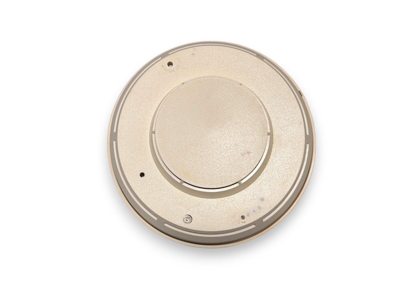 Beige circular fire alarm detector with mounting holes and indicator lights