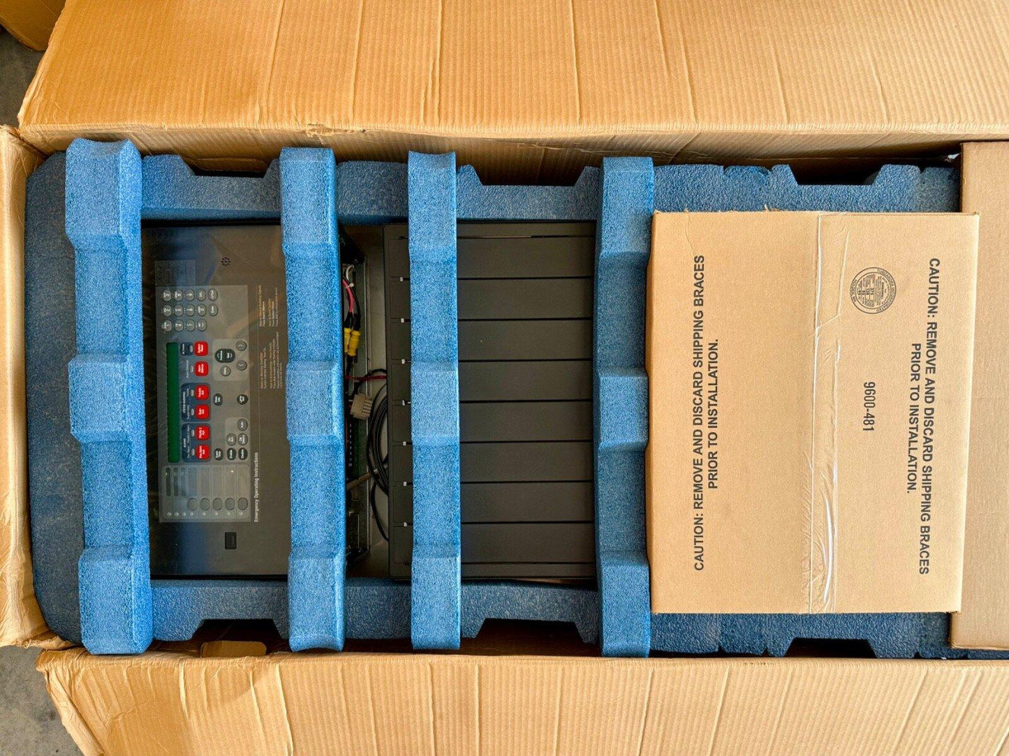 Fire alarm control panel in shipping box with blue foam protection and installation guide