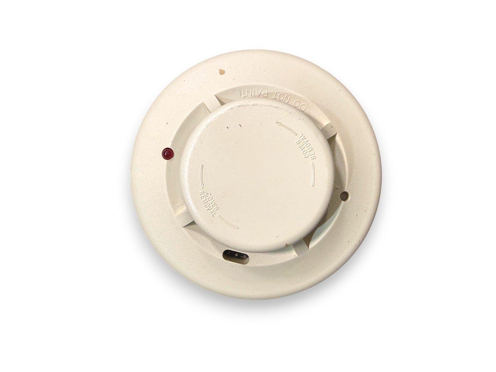 Used fire alarm smoke detector with red LED indicator, DO NOT PAINT label, and cover removal slots