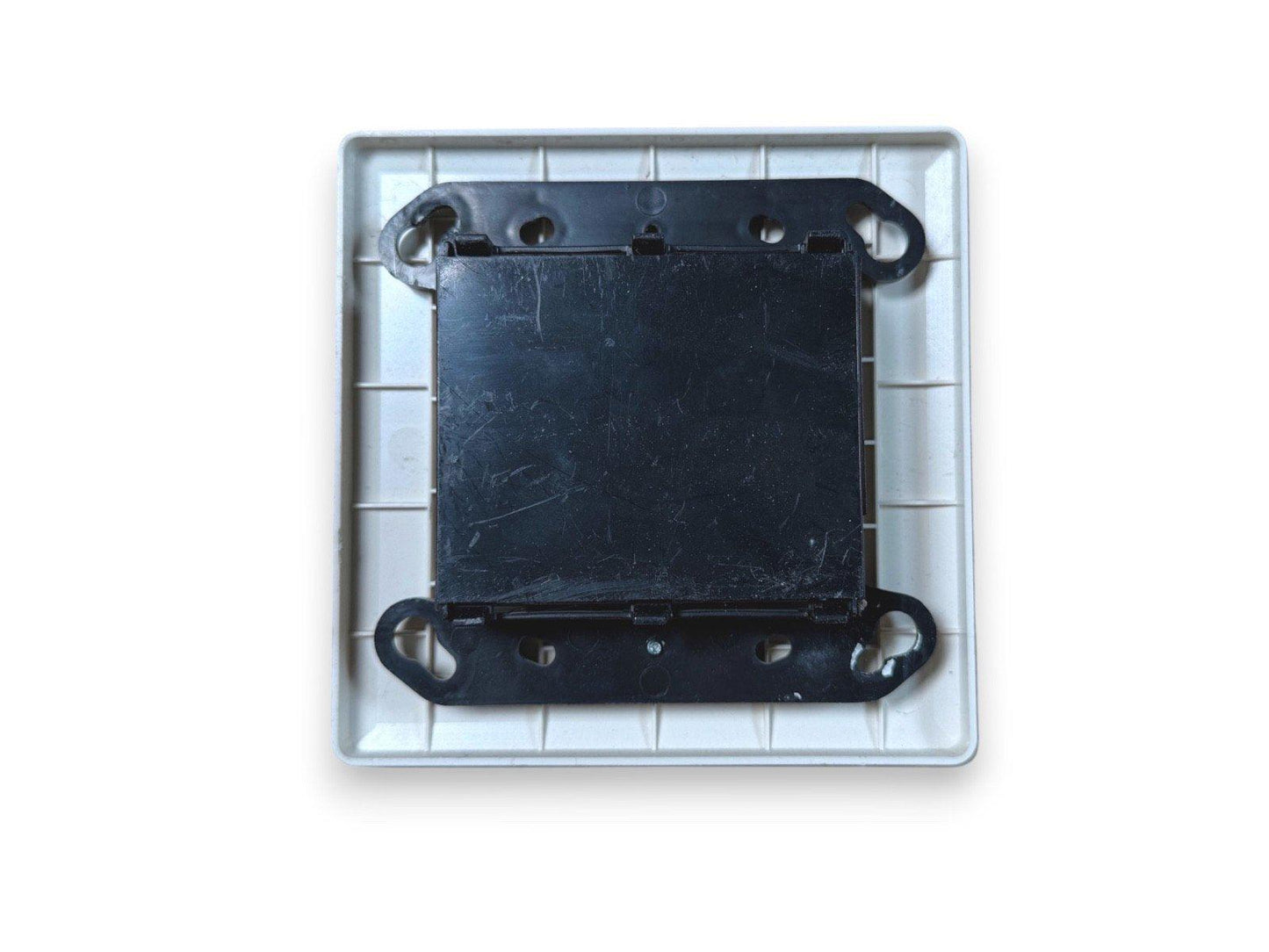 Black fire alarm base plate with mounting brackets in white housing