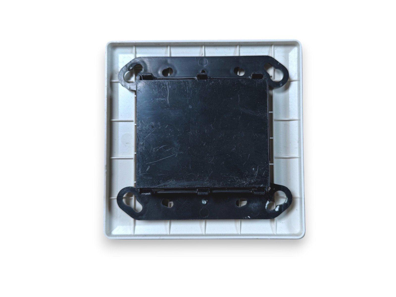 Black fire alarm base plate with mounting brackets in white housing