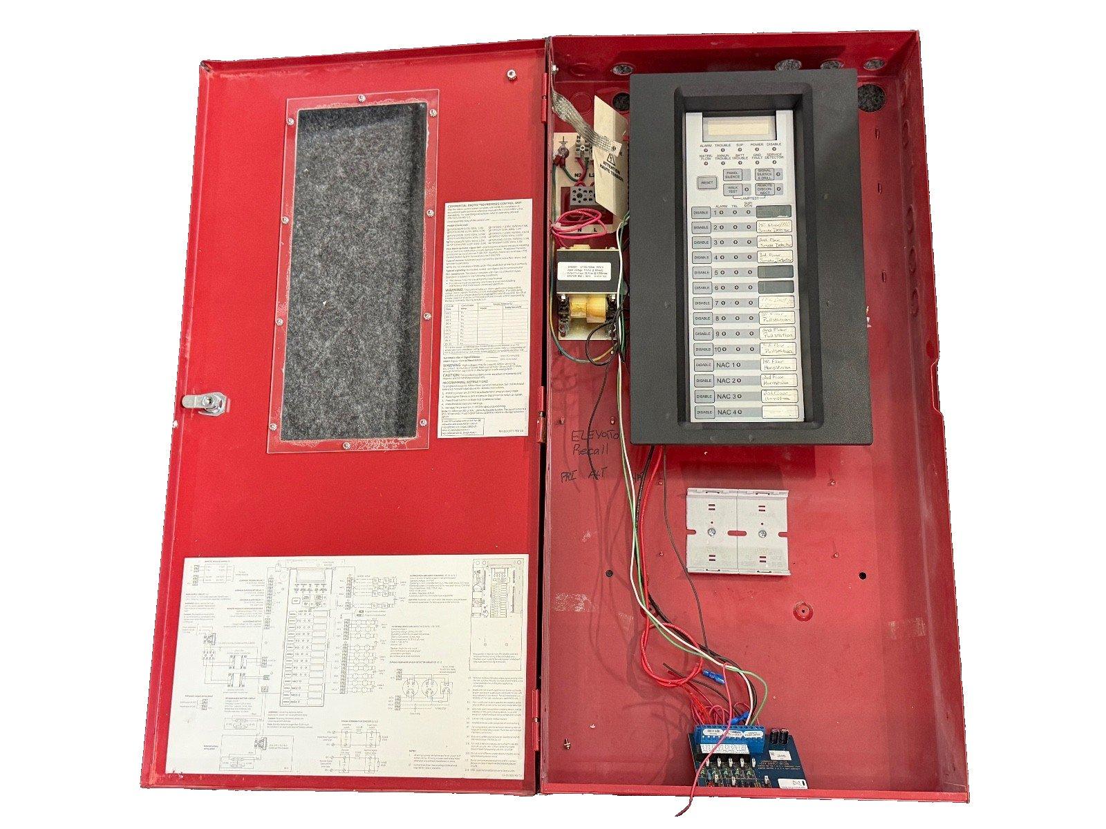 Red fire alarm control panel with open door, visible wiring, keypad, and circuit diagrams for commercial use