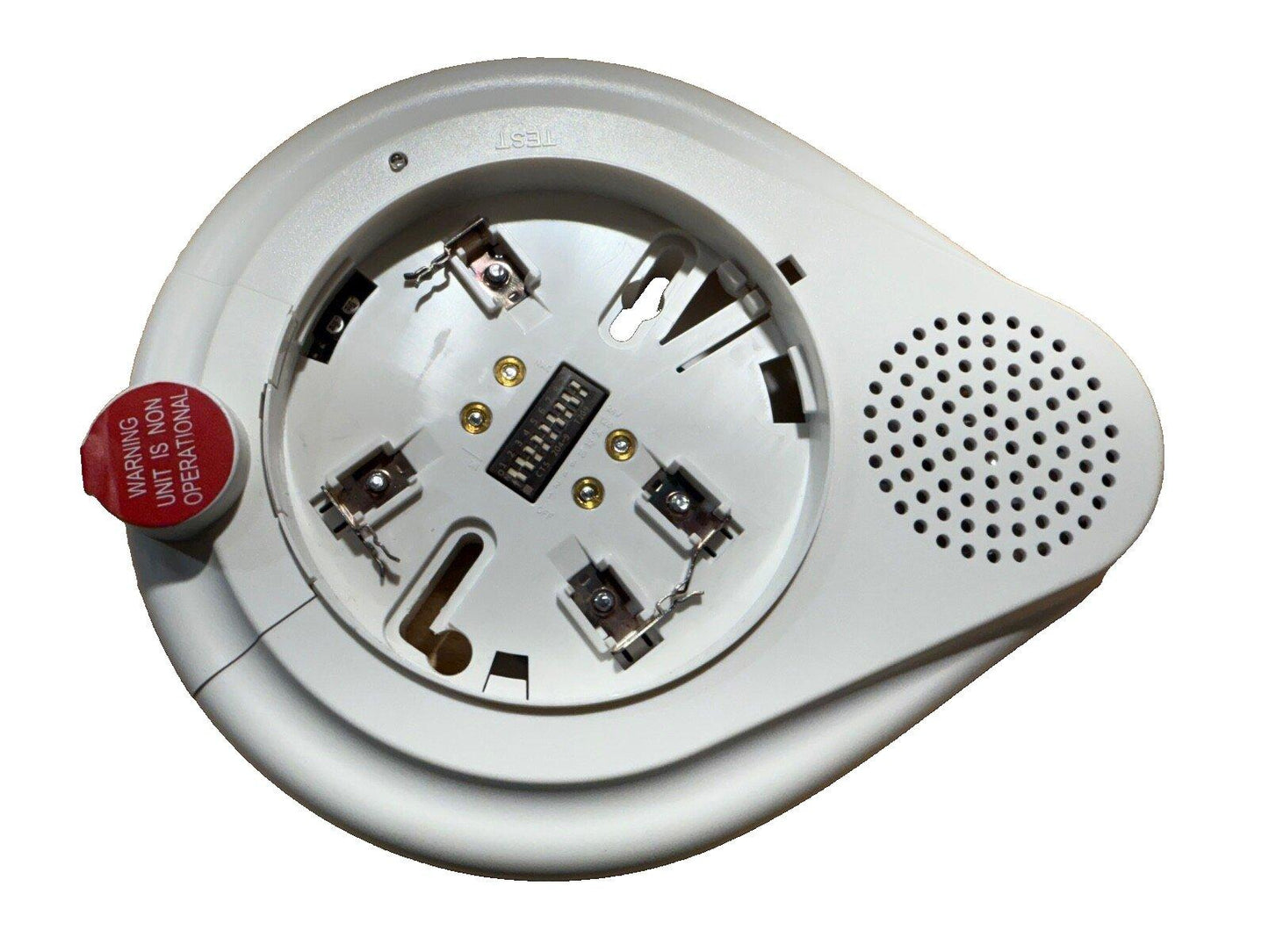 White fire alarm device with exposed wiring, test button, and speaker grille for safety systems