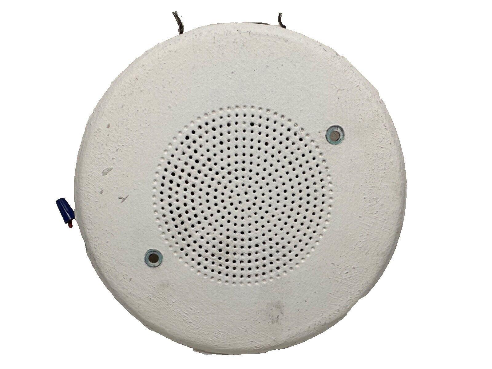 White circular fire alarm speaker with perforated grille and wiring, for commercial safety systems