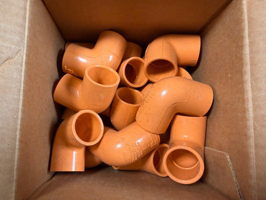 Orange PVC pipe fittings in cardboard box, fire alarm system components