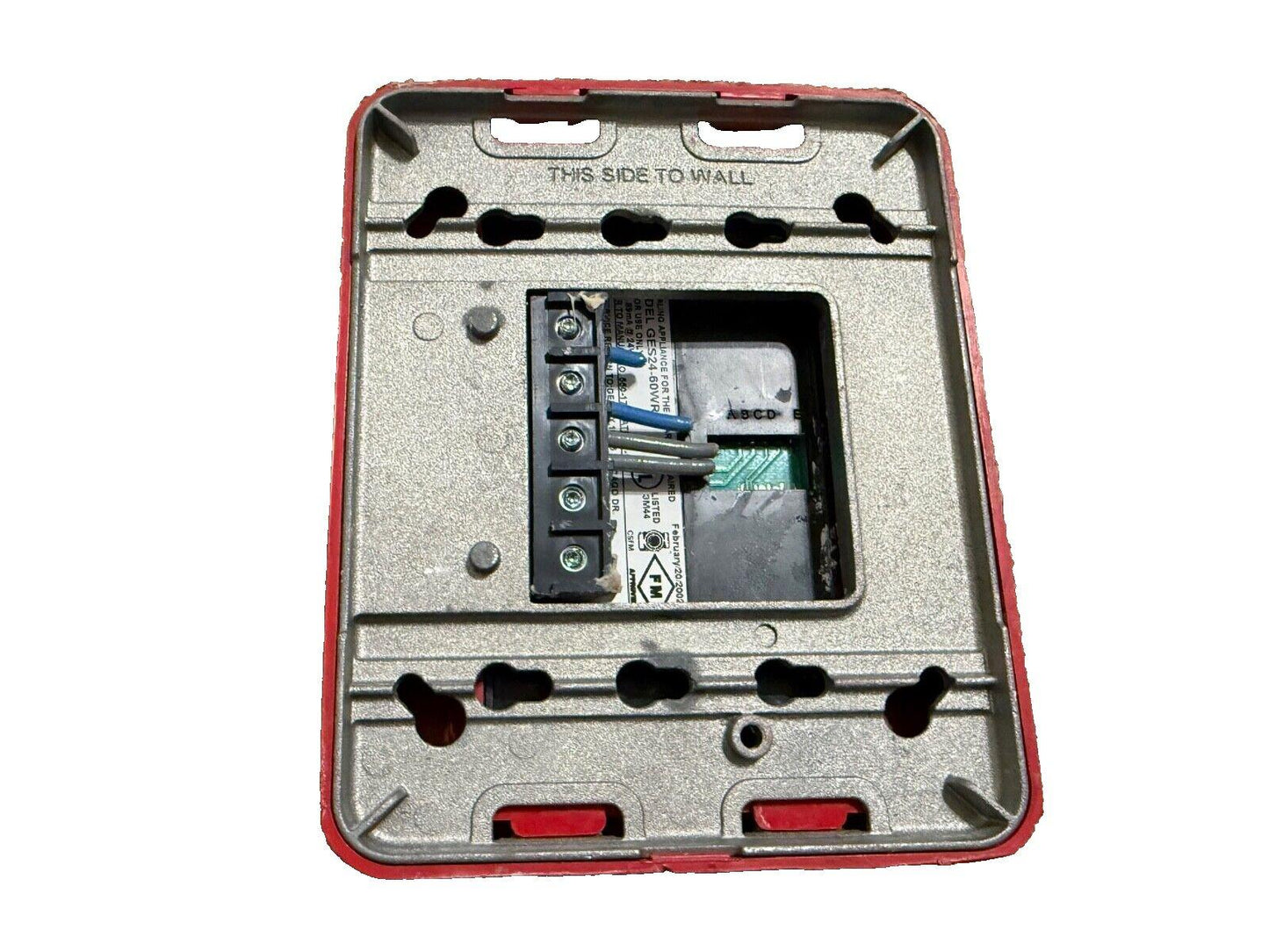 Fire alarm control panel back with wiring terminals and mounting holes, labeled 'THIS SIDE TO WALL'