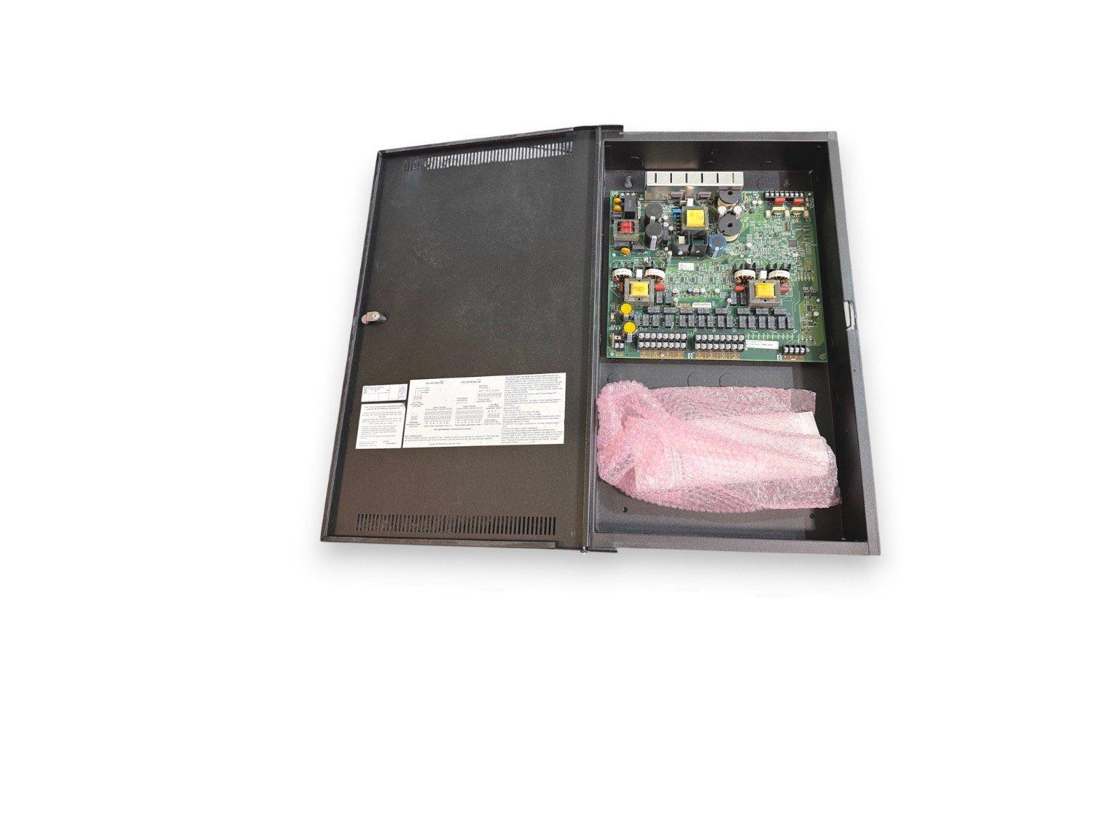 Open fire alarm control panel with circuit board and protective packaging inside metal enclosure