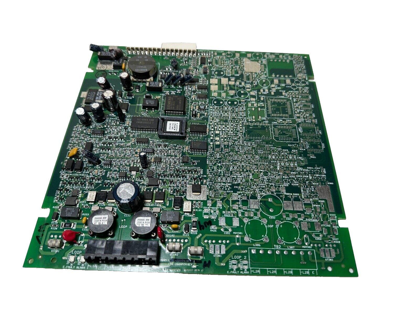 Fire alarm control panel circuit board with capacitors, chips, and loop connectors for fire safety systems