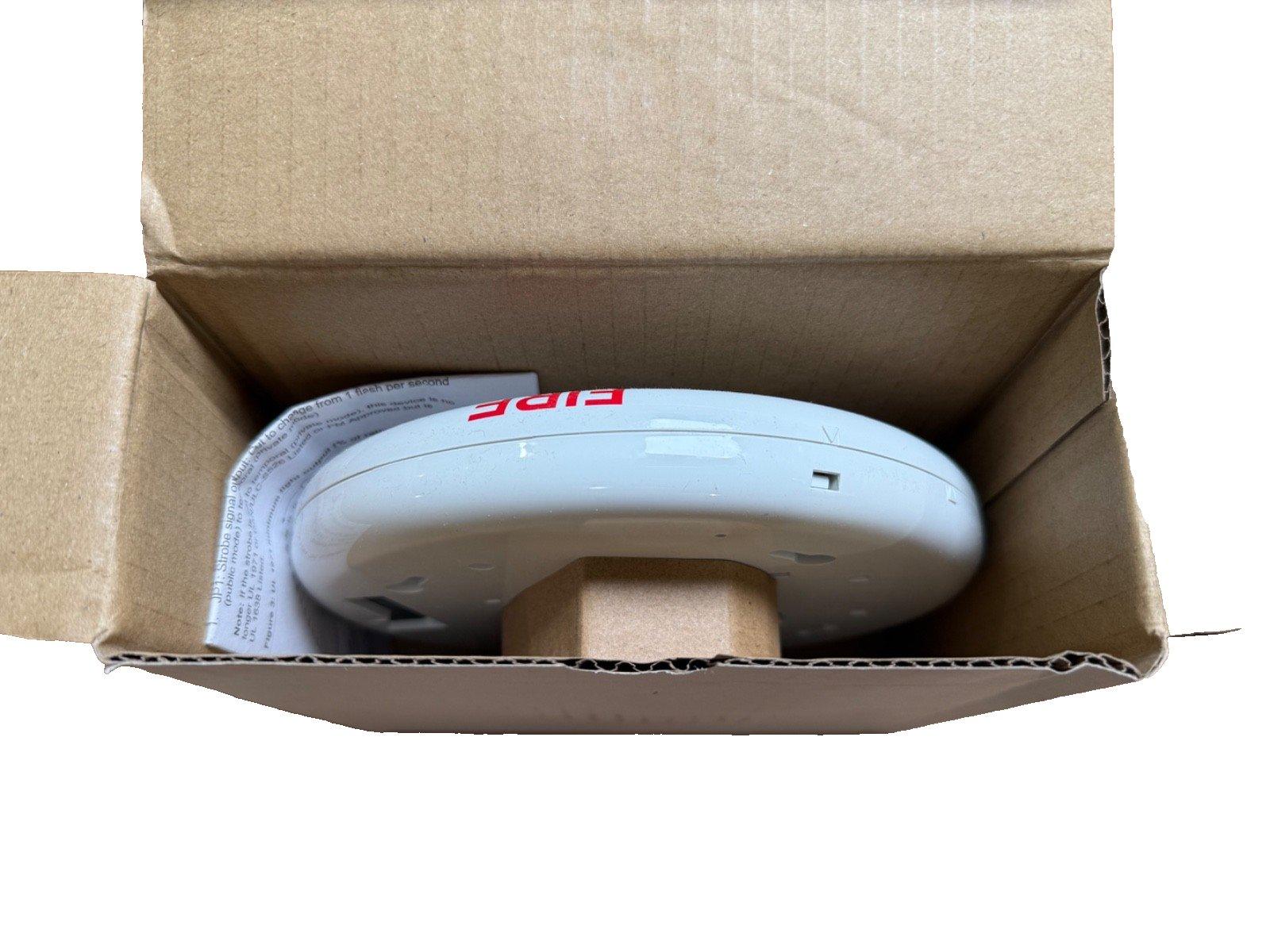White fire alarm strobe light in open box, labeled 'FIRE', for commercial or residential safety systems.