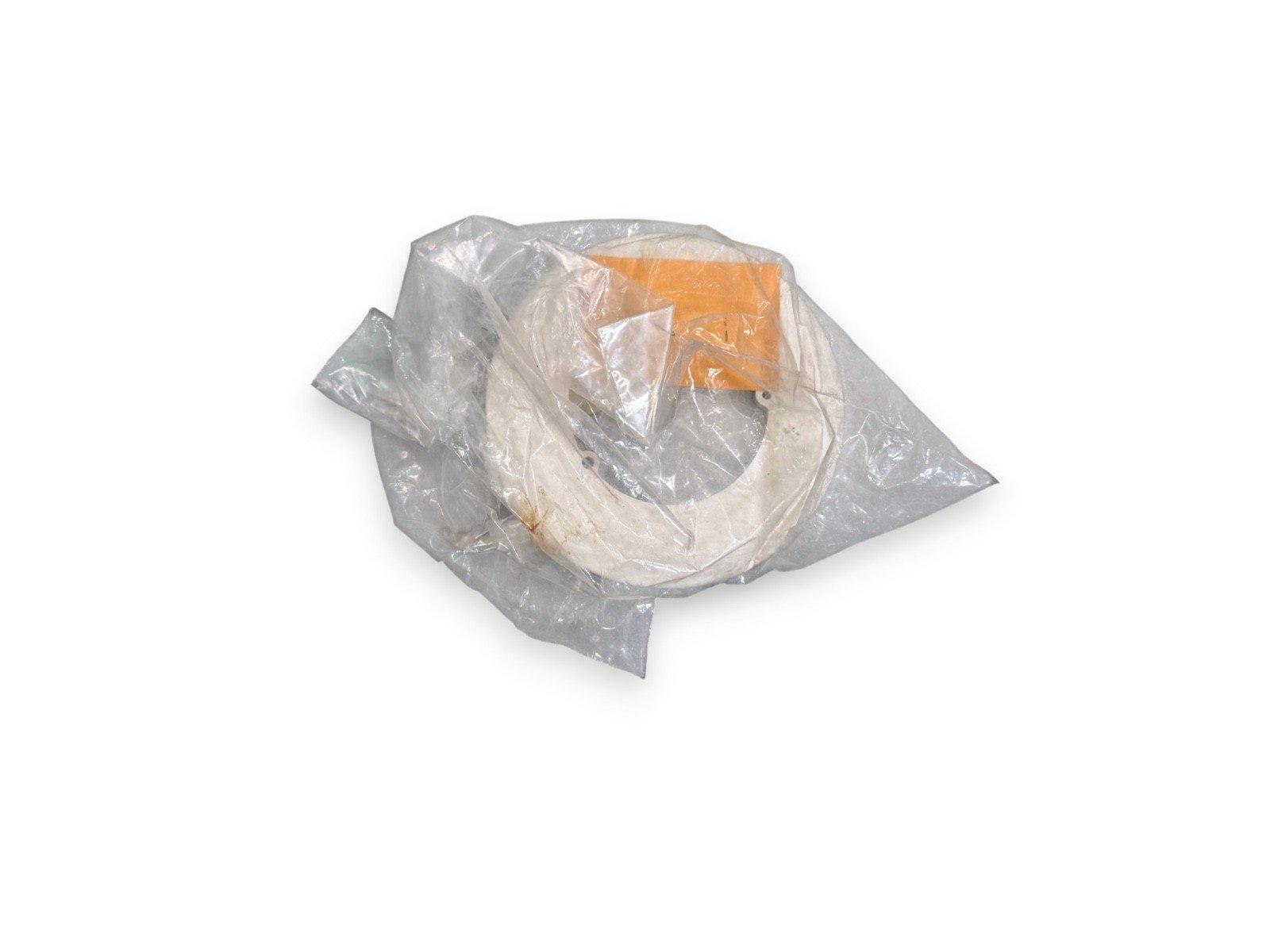 Used fire alarm component in plastic wrap, white circular part with orange label