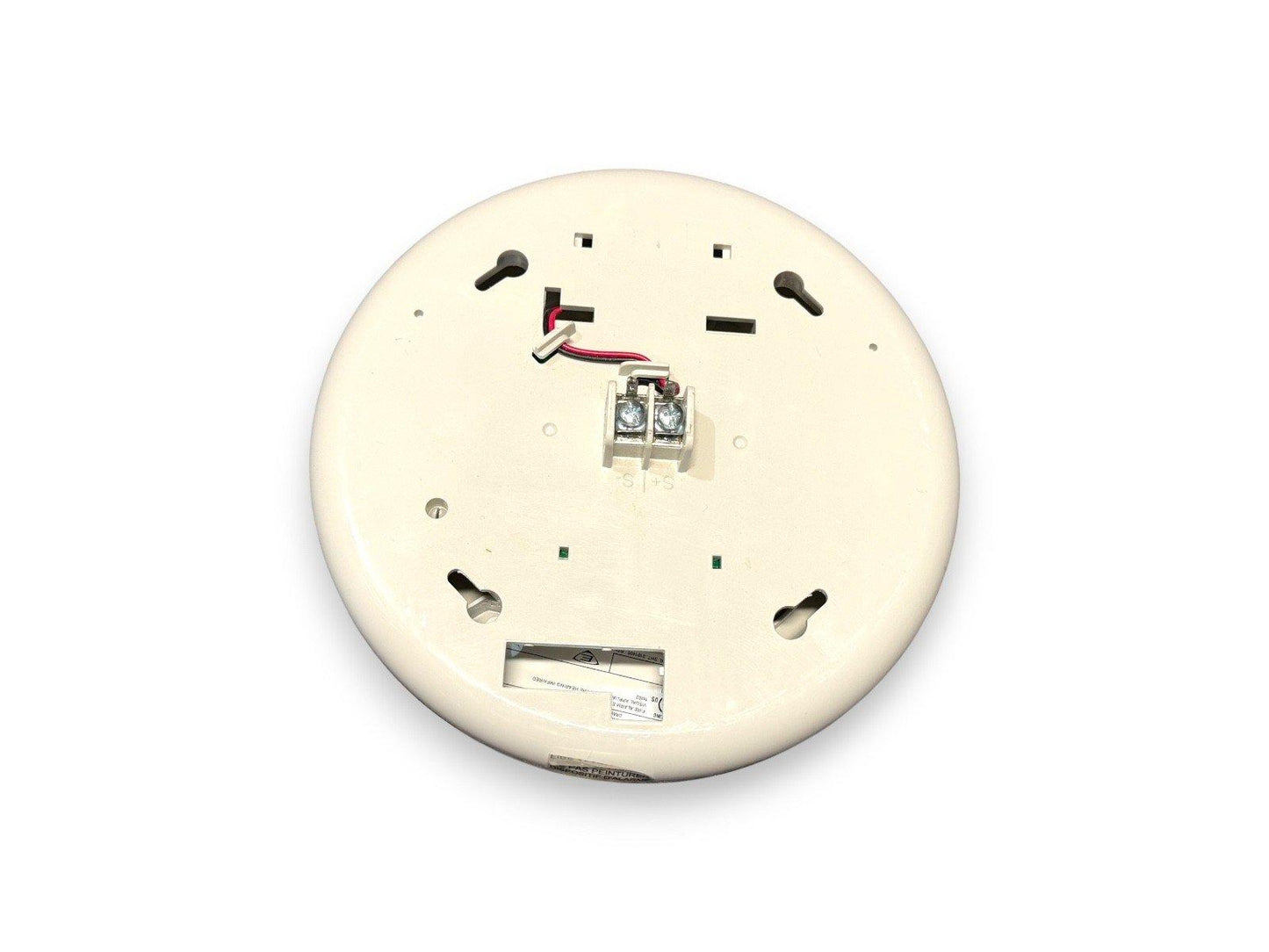 Back view of white fire alarm detector with wiring terminals and mounting slots