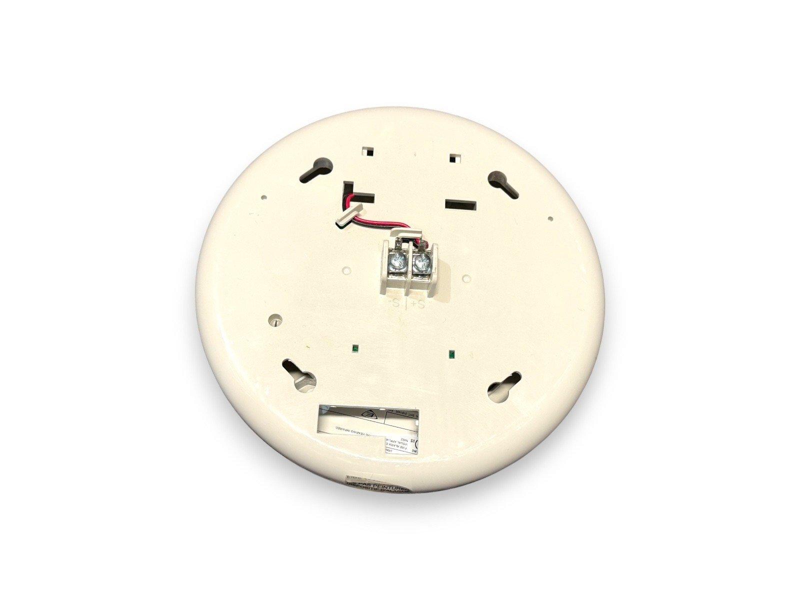 Back view of white fire alarm detector with wiring terminals and mounting slots