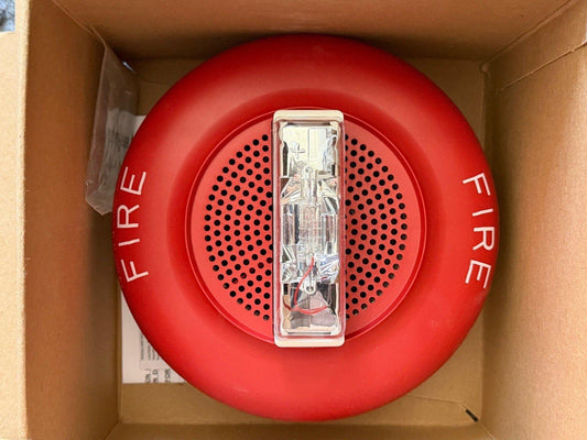 Red fire alarm horn strobe with 'FIRE' label, mounted in box, for commercial or industrial safety systems.