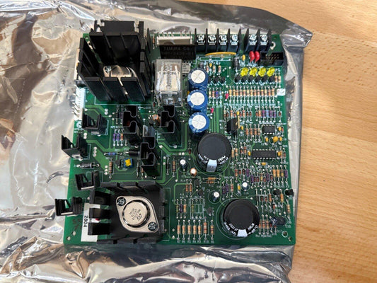Fire alarm control panel circuit board with capacitors, resistors, and heat sinks on green PCB