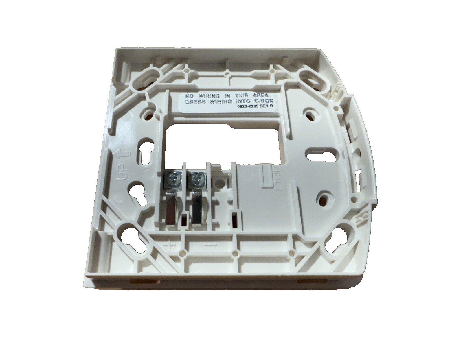Fire alarm control panel backplate with wiring terminals and mounting holes, labeled for E-box installation