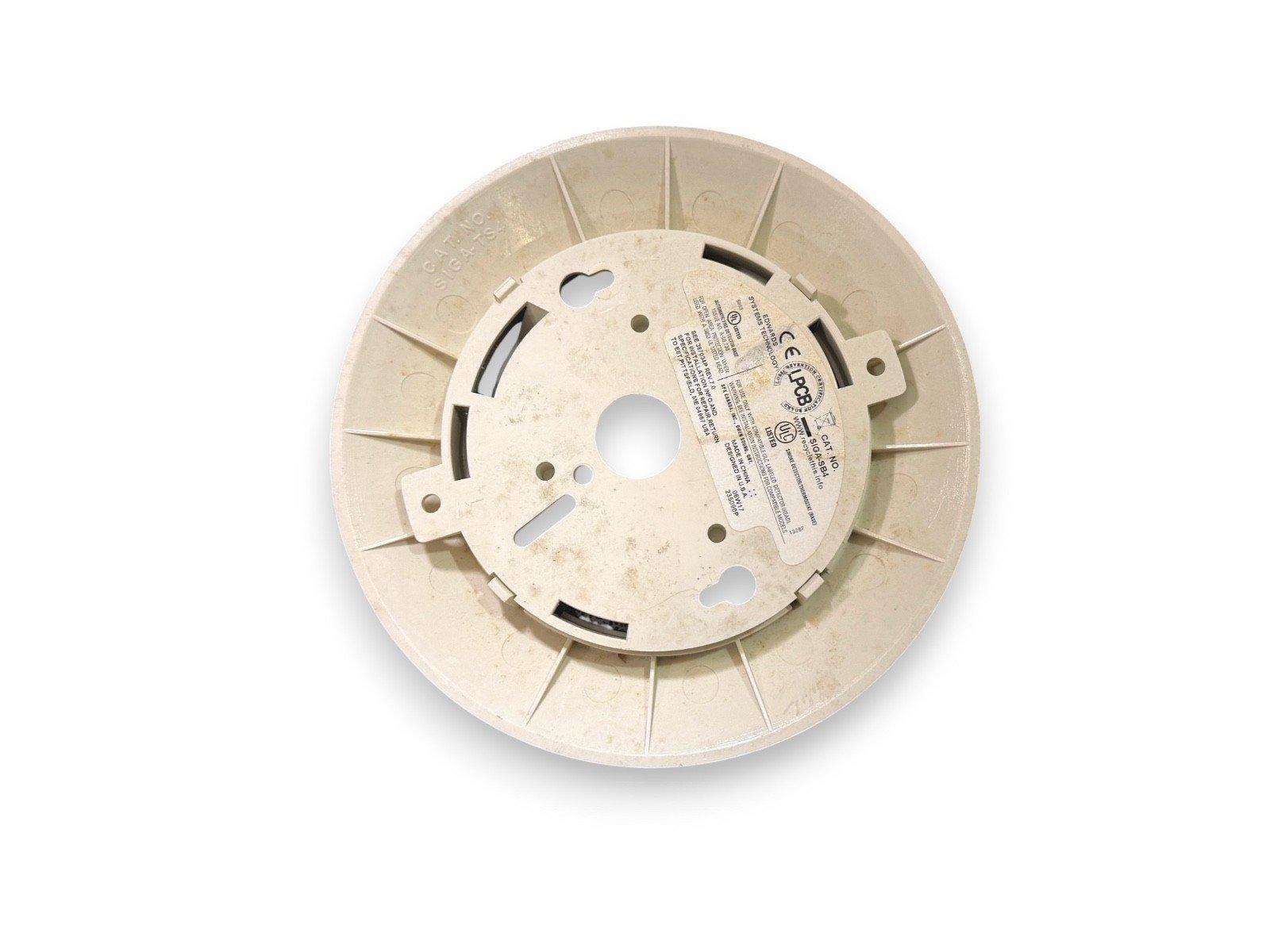 Used fire alarm base plate with mounting slots and certification labels, compatible with smoke detectors