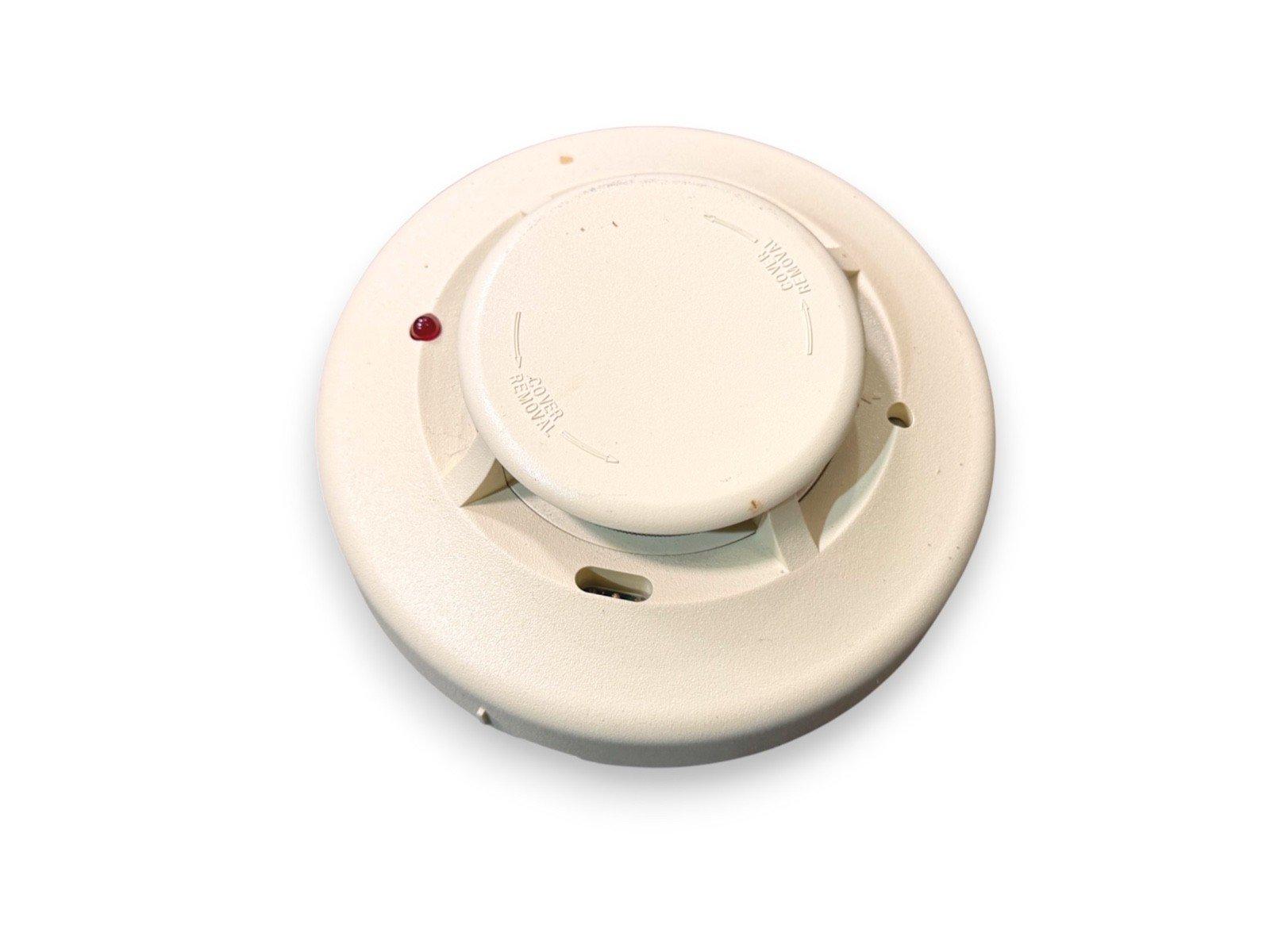 White ceiling-mounted fire alarm detector with red LED indicator, used fire safety equipment