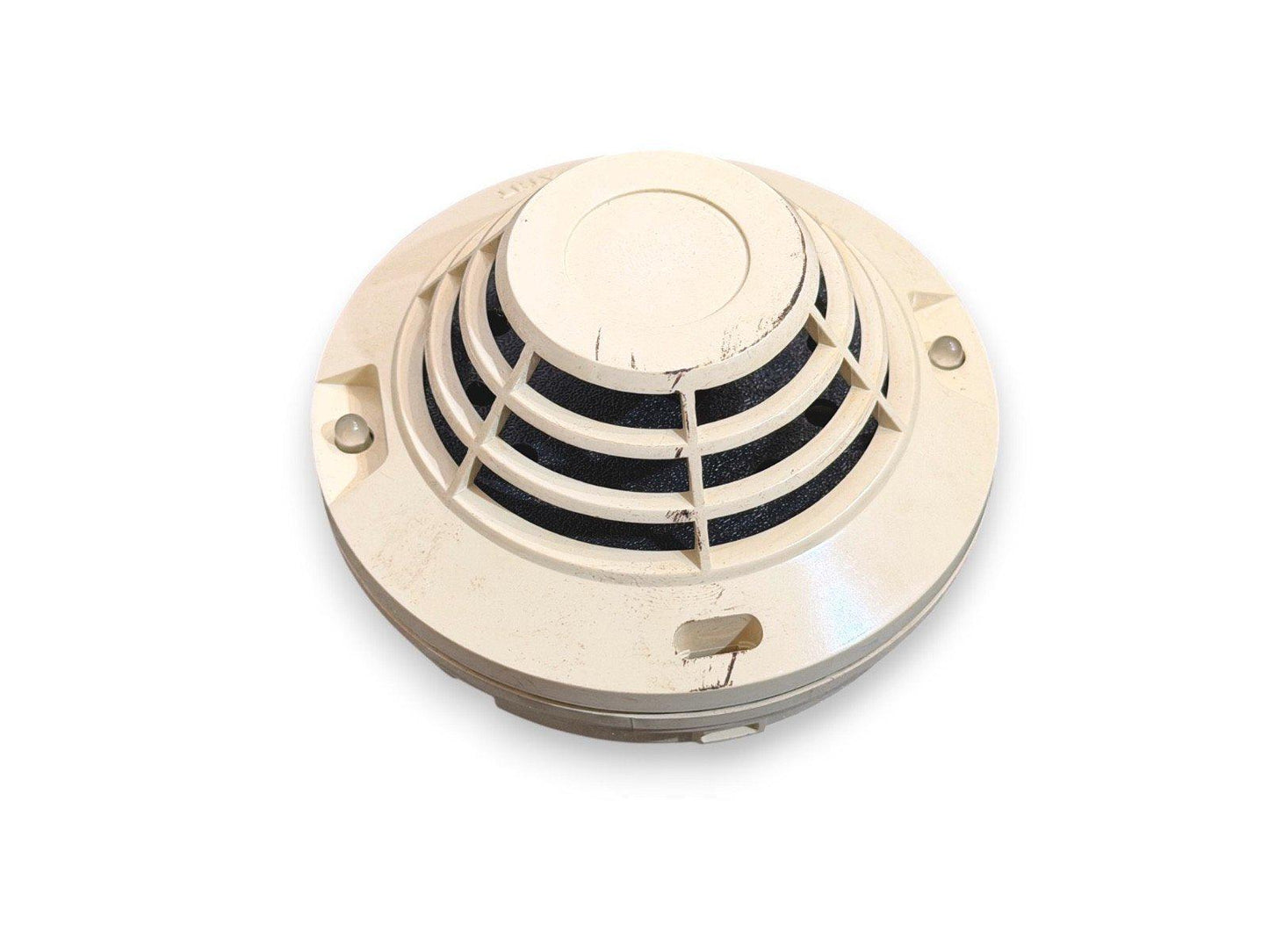 Used fire alarm smoke detector with grille cover, off-white housing, and mounting screws visible